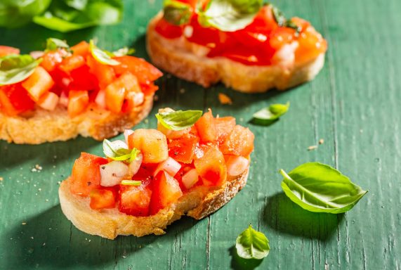 Antipasti Bruschetta mit frischen Tomaten, Olive und Basilikum auf knusprigem Brot.